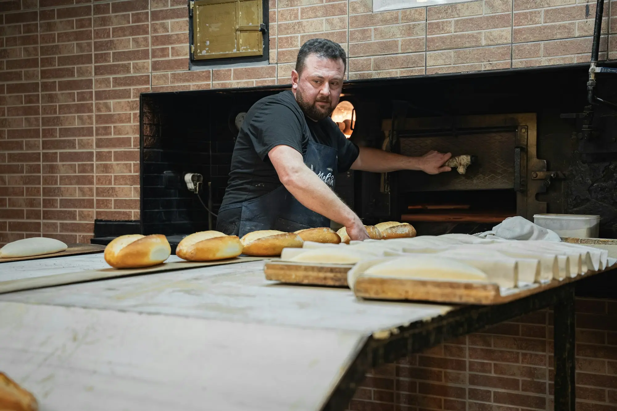 Baker/bakery owner loading a deck oven in a working bakery