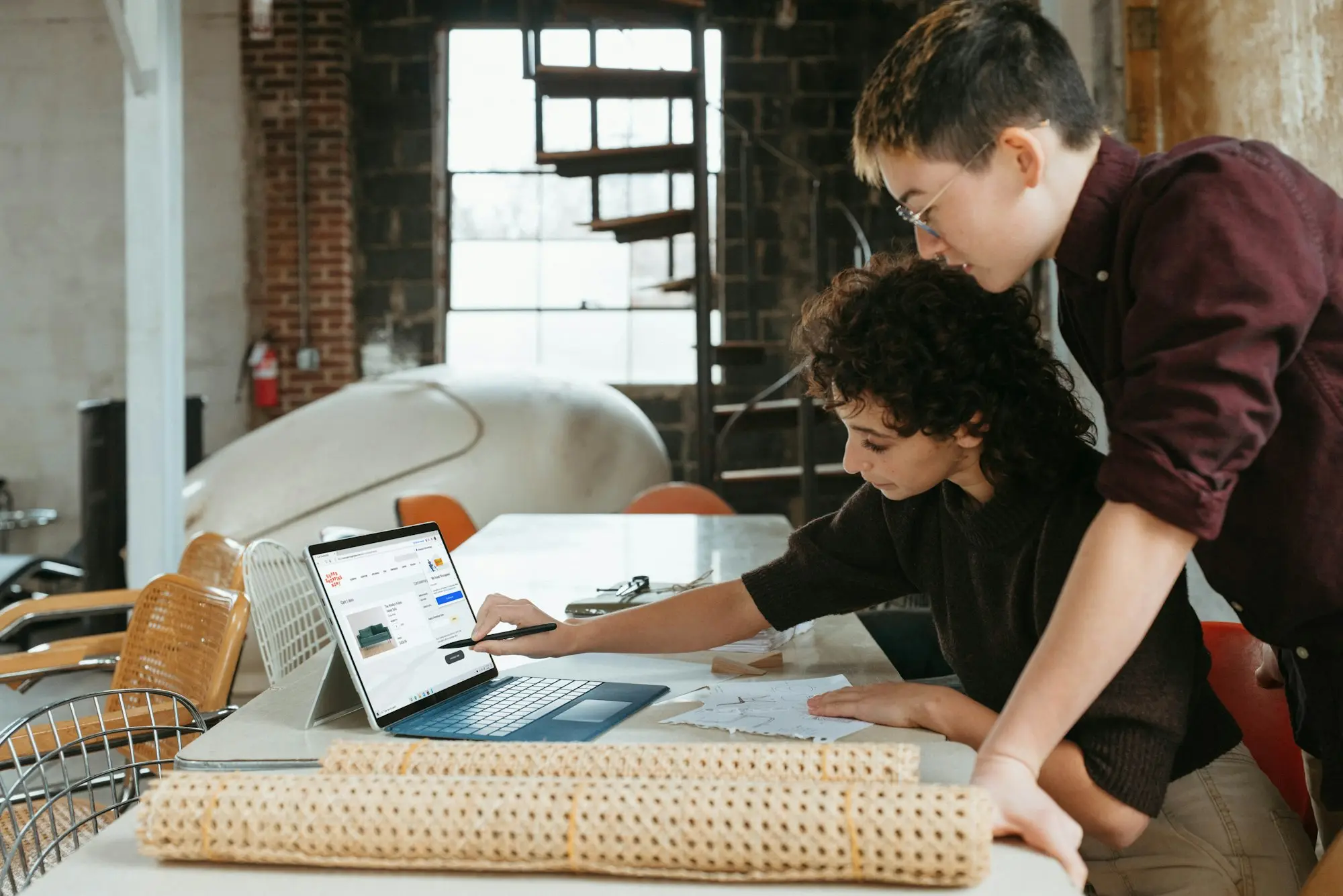 Two Australian small business owners (mixed ages) at a bright office table with a laptop and notebook