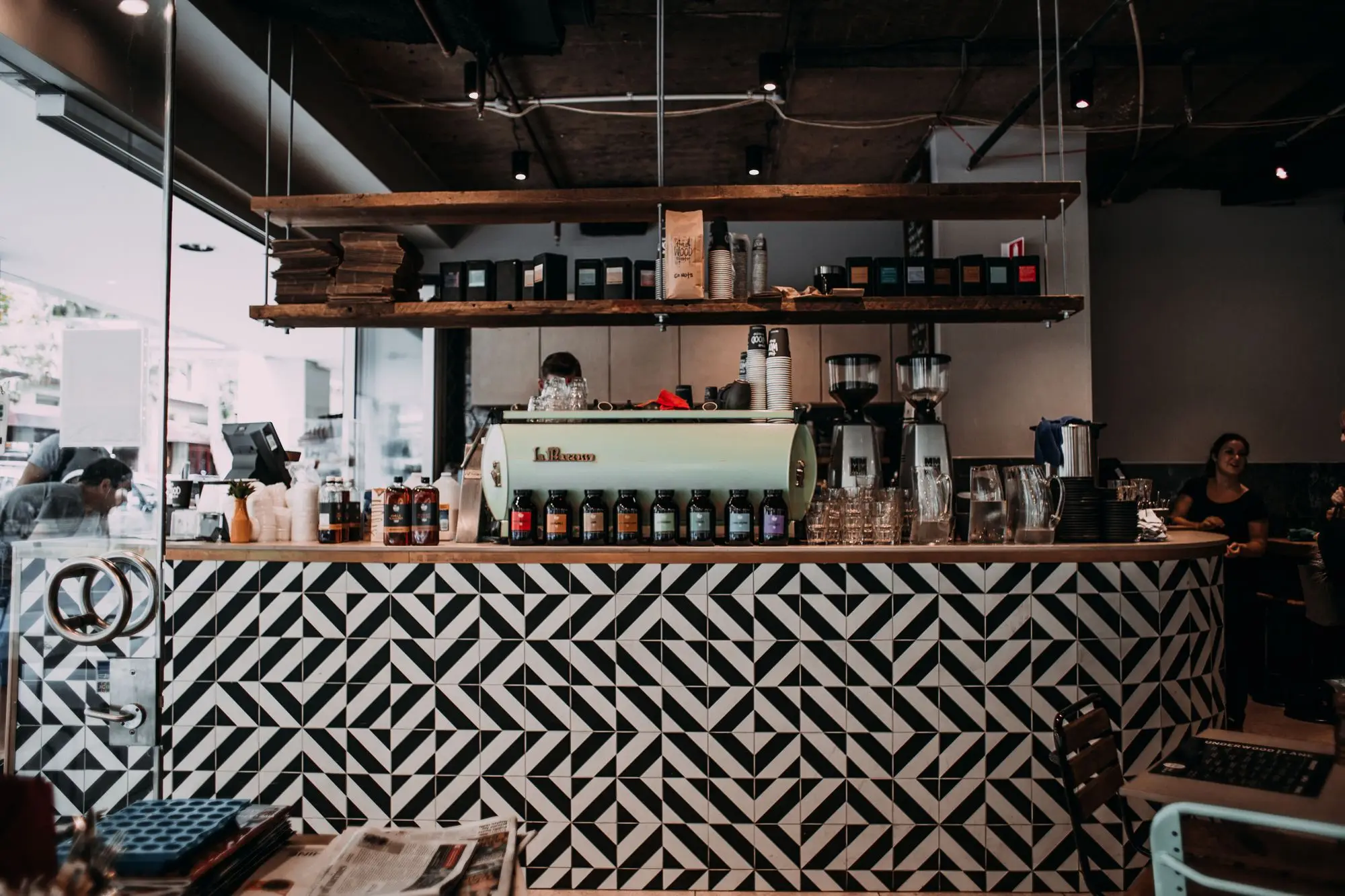 Busy established café with a patterned tiled counter, espresso machine and staff at work — the kind of trading business buyers pay goodwill for